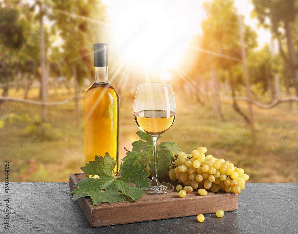 Naklejka premium Wine and fresh grapes on table. Glass and bottle in sunny vineyard