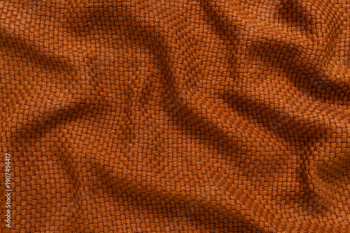 Detailed texture of golden orange woven fabric background. Top view of warm ochre colored thick throw blanket with a basket weave pattern, softly draped to create an abstract background