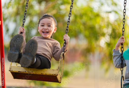 cheerful child girl playing on swing at playground