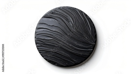 Circular black object with textured, wavy surface, set against a bright white backdrop