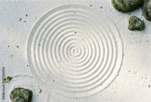 Top view of zen sand garden with spiral pattern and stones