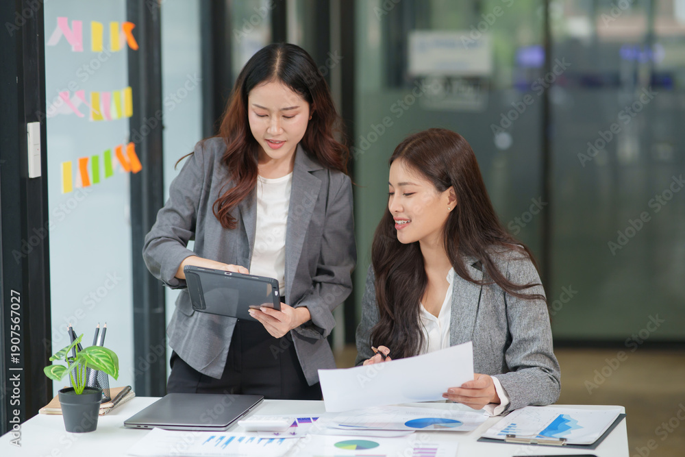 © aekachai - Two Asian businesswomen working with documents in an office. © aekachai - Two Asian businesswomen working with documents in an office.
