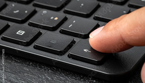 Close-up of a finger pressing the enter key on a black keyboard, technology concept.