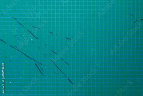 Textured green cutting mat with grid pattern, scratches, and abstract marks. Perfect for backgrounds, textures and craft
