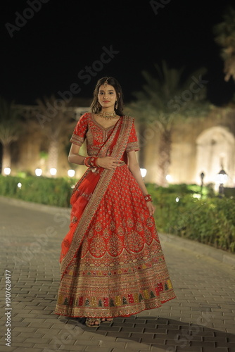 Young Indian Woman Wearing Traditional Red Bridal Lehenga at Night Outdoors
