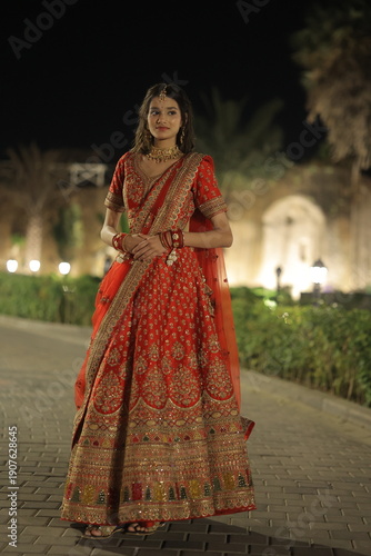 Young Indian Woman Wearing Traditional Red Bridal Lehenga at Night Outdoors