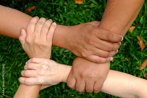 Four people hands holding wrists in a square shape, teamwork and unity concept, group of friends or partners showing support and power and collaborate within the organization.