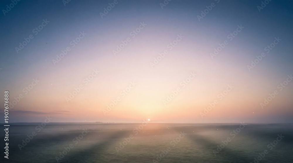 Obraz premium A serene sunrise over a vast ocean with gentle waves and soft light rays emanating from the horizon viewpoint