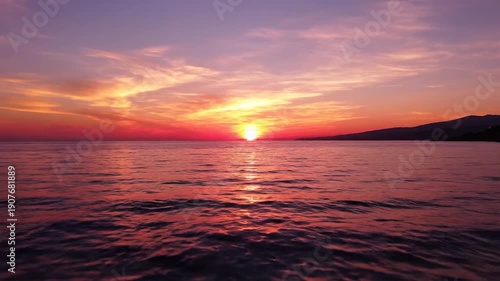 Vibrant orange and purple sunset paints the sky over the calm ocean waters