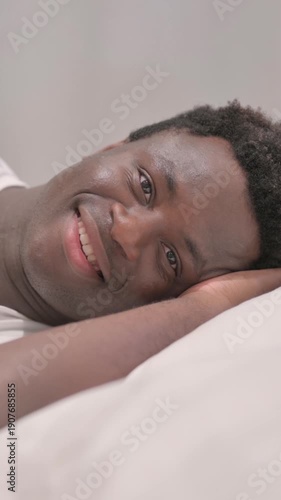 Smiling African American Man Lying in Bed on Side, vertical video