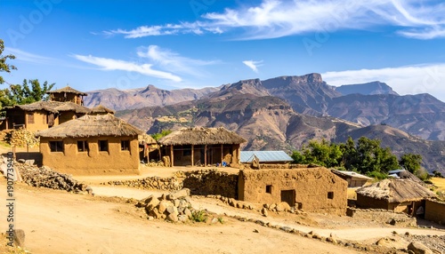 African village houses with thatched roofs in mountainous landscape under blue sky
