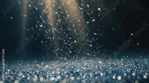 Glittery particles in air with rays of light and a blurred, textured surface below