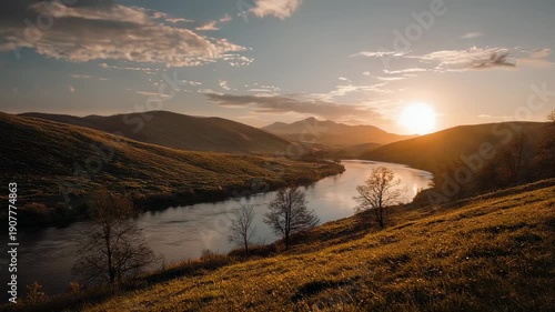 Golden sunset over a winding river through rolling hills, with a few trees