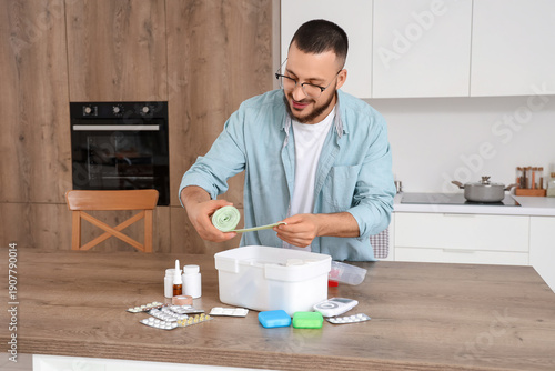 Young man taking bandage fr...