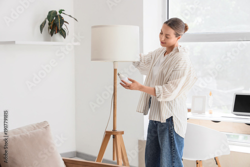 Young woman screwing light ...