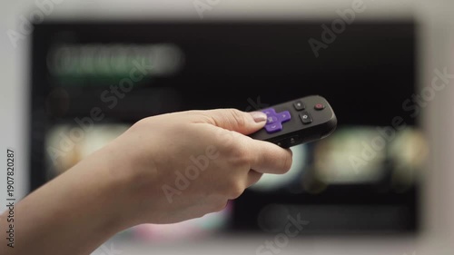 Wallpaper Mural Woman's hand holding a streaming device remote control changing channels on a smart tv in a living room at home Torontodigital.ca