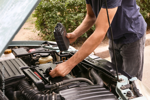 Male mechanic refilling car...