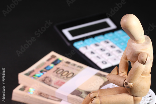 札束と電卓と木製人形のビジネスイメージ