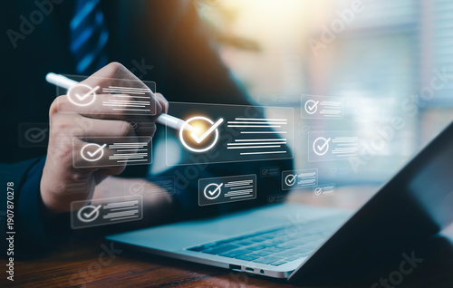 Business professional using digital checklist and virtual approval interface on laptop, concept of quality control, compliance management, workflow automation, and business technology innovation.