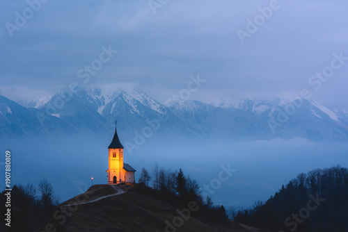 Wallpaper Mural Jamnik Church rises above the misty hills on a calm Slovenian winter morning Torontodigital.ca