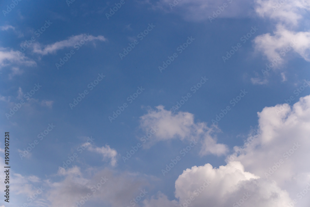 Fototapeta premium Blue sky background with scattered white fluffy clouds