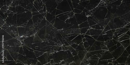 a black glass screen that is cracked and shattered into pieces on a dark background
