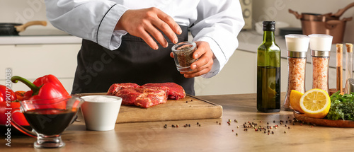 Male chef peppering raw mea...