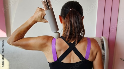 Wallpaper Mural Percussion massager young woman massaging shoulder after workout Torontodigital.ca