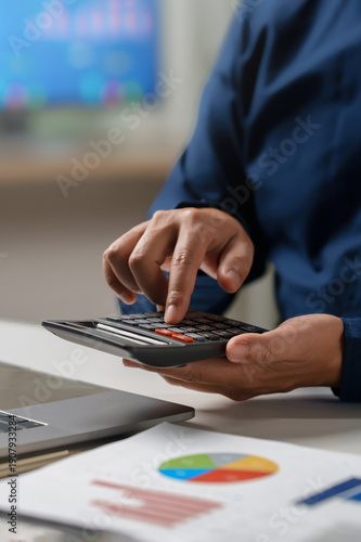 Business accounting concept, Business man using calculator with computer laptop, budget and loan paper in office. Doing finance, budgeting and tax calculation, monthly expenses. finance investment.