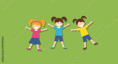 Three happy little girls are lying on the green grass in the shape of a star enjoying a sunny day outdoors together.