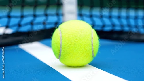 Tennis ball on blue court close to net, sport equipment for match or practice, showing focus on game concept