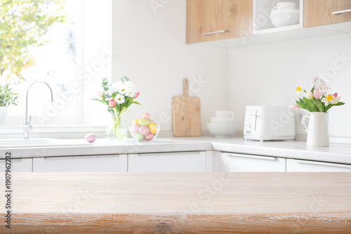 Bleached wooden table top on interior background of blurred kitchen counter decorated for Easter