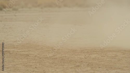 Dust cloud rising on barren desert landscape during dry season  
