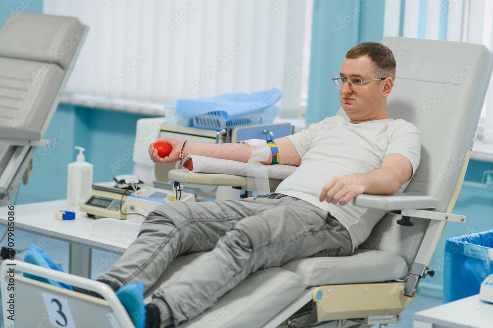 Fototapeta premium Male blood donor sitting in chair at clinic