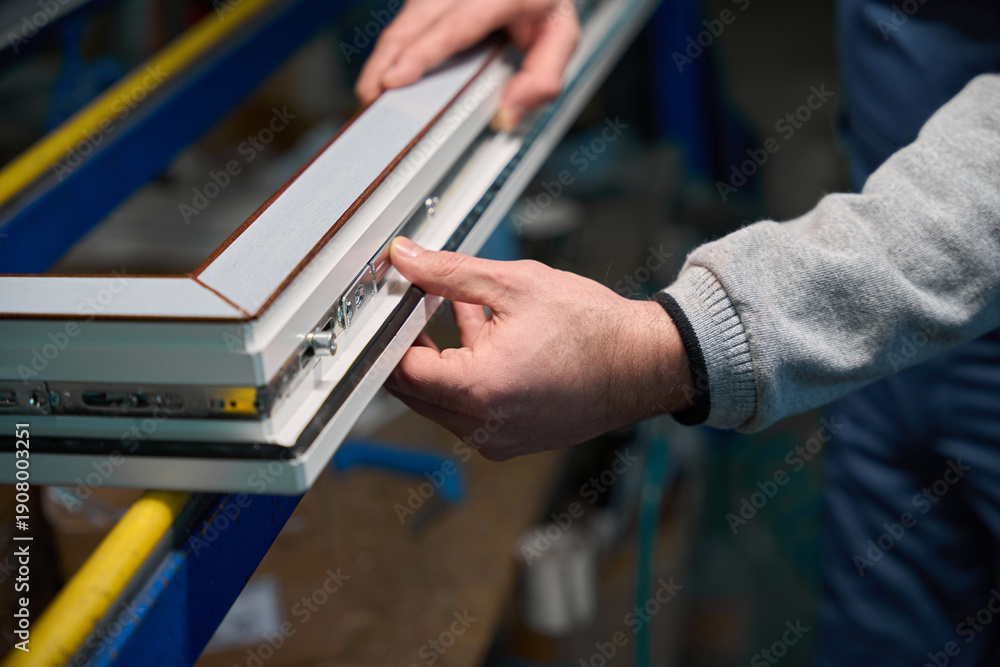 Naklejka premium Professional man worker engaged in assembly of PVC doors and windows