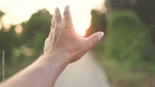 Hand reaching toward warm sunset light on a rural path, Hope concept, A hand reaching the glowing sunset, creating a warm, dreamy atmosphere with soft focus and natural light