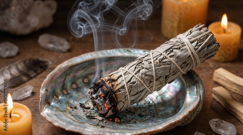 Smudging sage bundle producing smoke on abalone shell with candles  