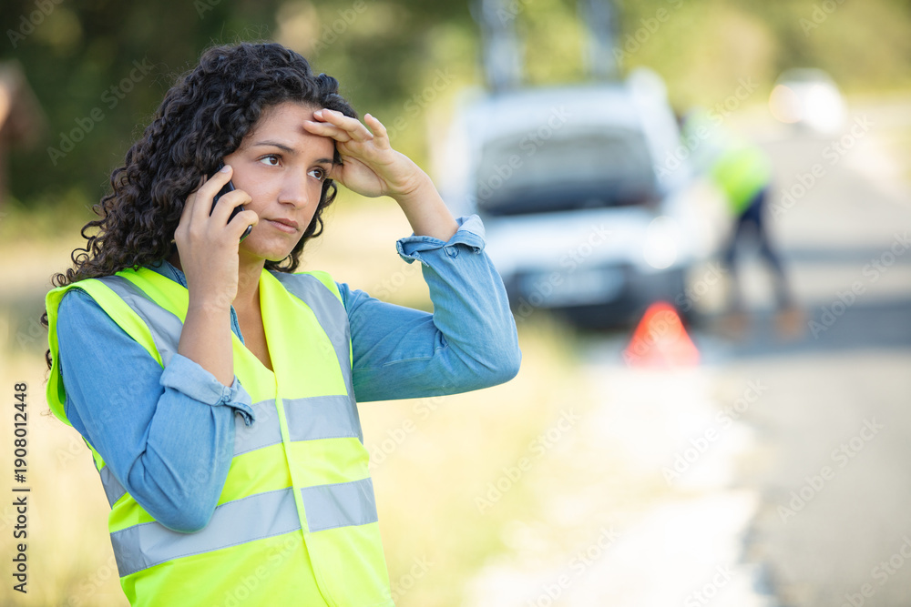 Fototapeta premium broken down woman wears reflective vest while phoning for assistance