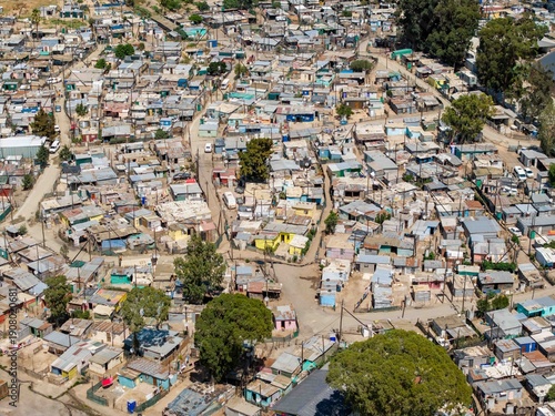 Aerial view of a densely packed township with corrugated iron roofs reflecting the harsh sunlight, Cape Town, South Africa.