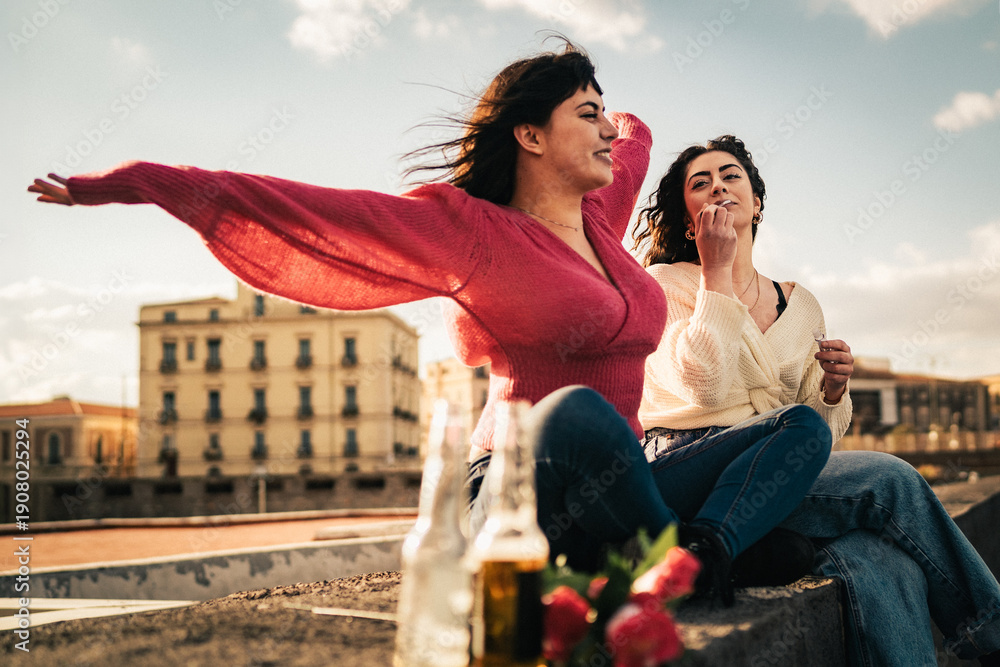Naklejka premium Two young women enjoying freedom together on rooftop at sunset