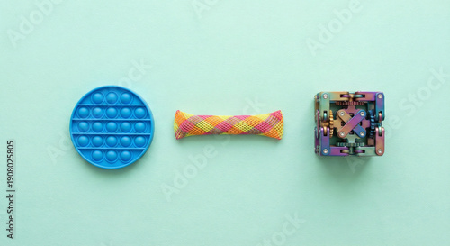 Set of sensory fidget toys including pop it, marble mesh and infinity cube on green background