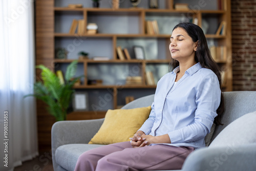 Photos Woman sitting on a couch with her eyes closed, calmly focusing on her breath and