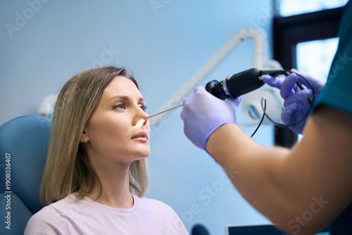ENT doctor otolaryngologist with headlight treat nose woman patient