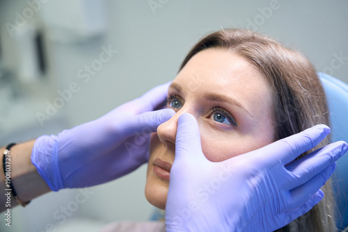 ENT doctor examines and palpates the nasal septum of female patient