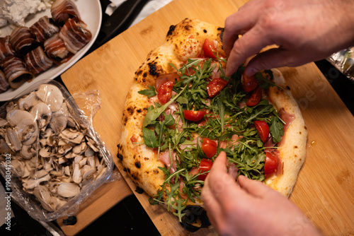 Εκτύπωση καμβά Hands topping fresh homemade pizza with arugula and tomatoes