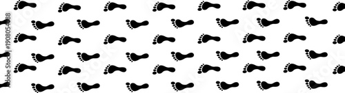 Dense pattern of black bare footprints covering a white surface, evoking a sense of many steps.