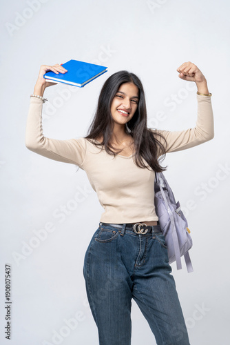 young indian college girl standing with book and bag on white background