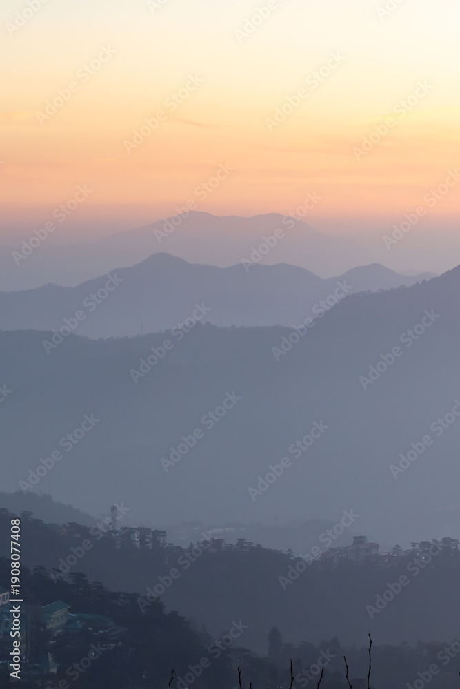 Obraz premium misty mountain landscape at dawn with orange sky and layered hills