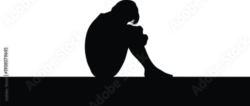 A person sitting alone on the ground viewed from behind in a melancholic pose with sadness despair loneliness sorrow grief