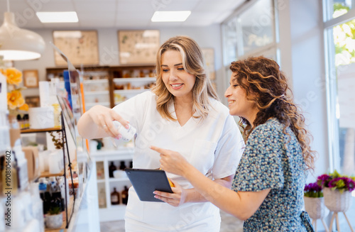 Female pharmacist helping woman to choose medication in pharmacy.